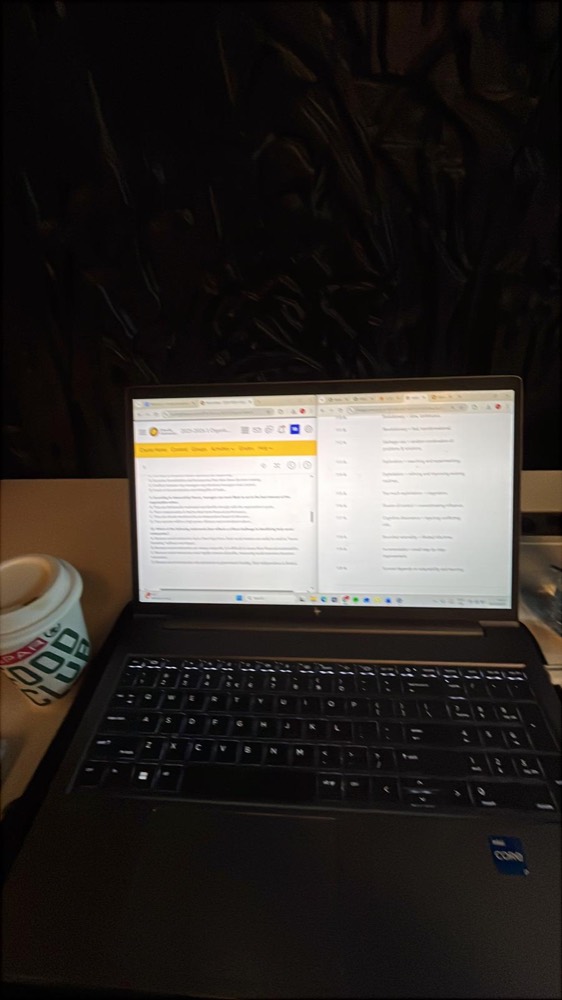 Een laptop bij avondlicht met een openstaand document op het scherm, naast een beker koffie
